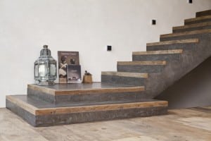 eine graue Treppe mit Holzkanten vor einer beigen Wand